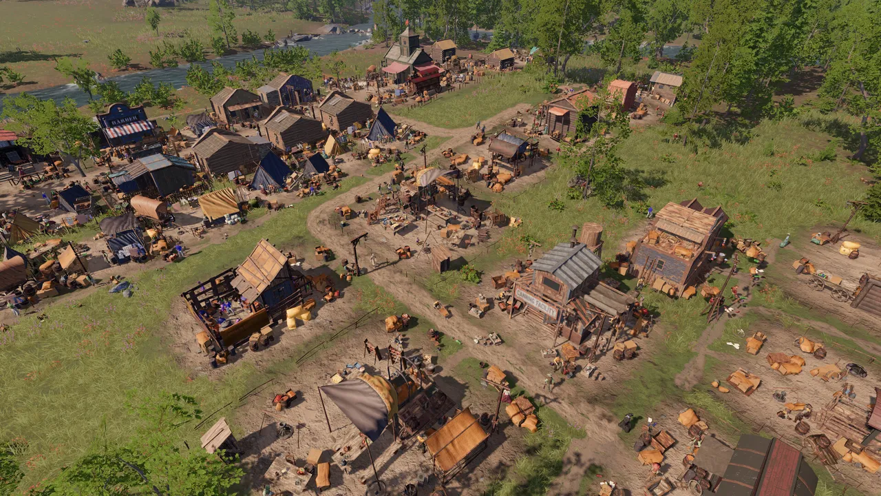 A settlement of tents and wooden cabins on green ground near a river
